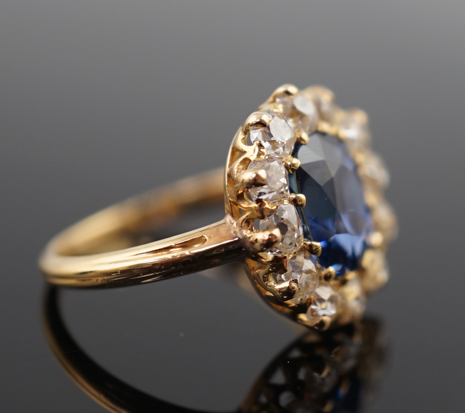 A gold, sapphire and old round cut diamond set oval cluster ring